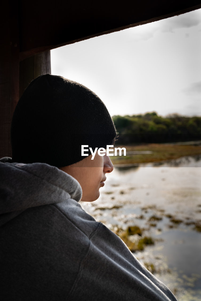 Young man looking at the lake at sunset