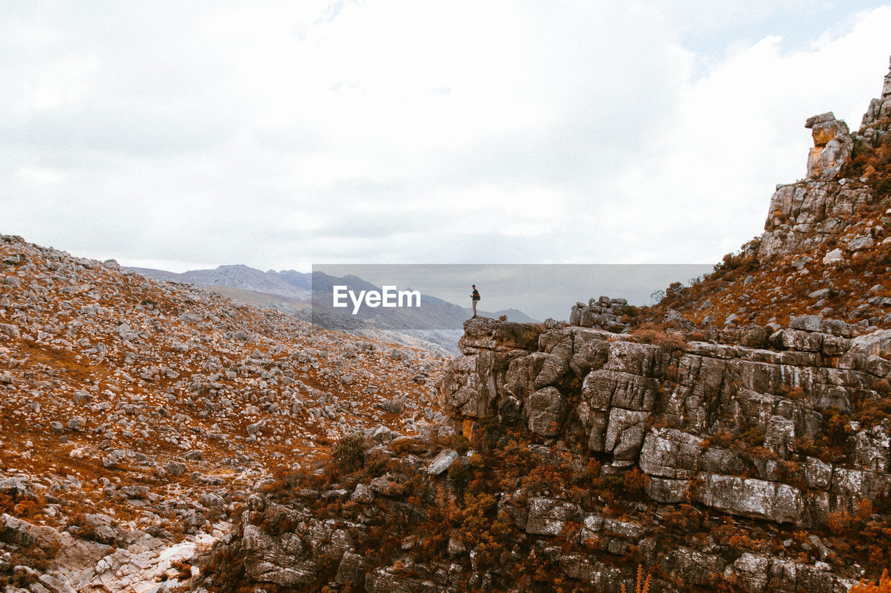 Person on cliff against sky