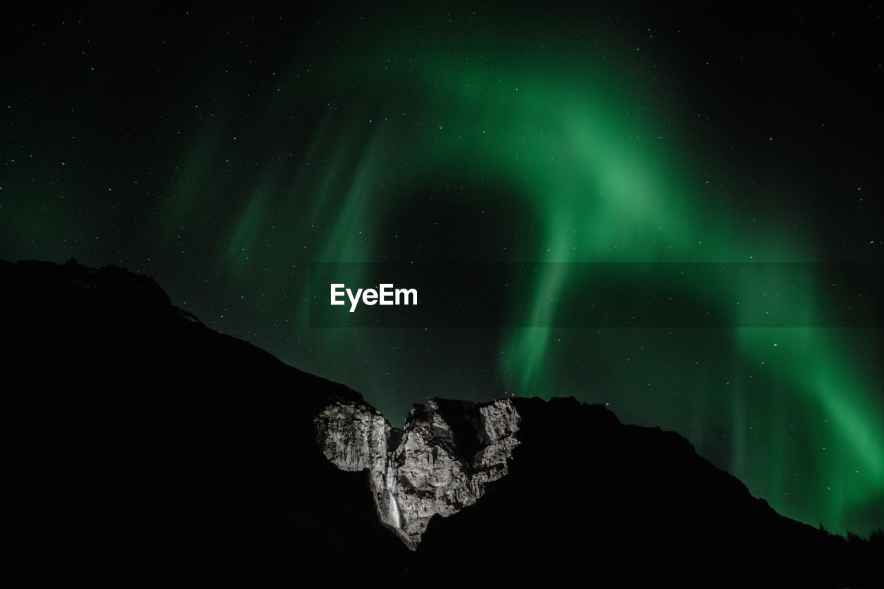 Low angle view of mountain against aurora polaris