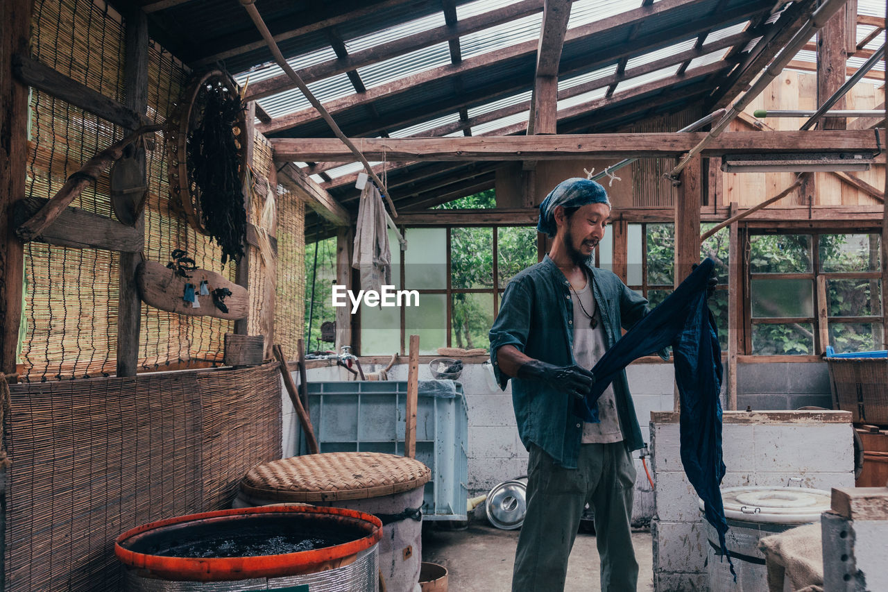 Man holding clothing while standing in shed