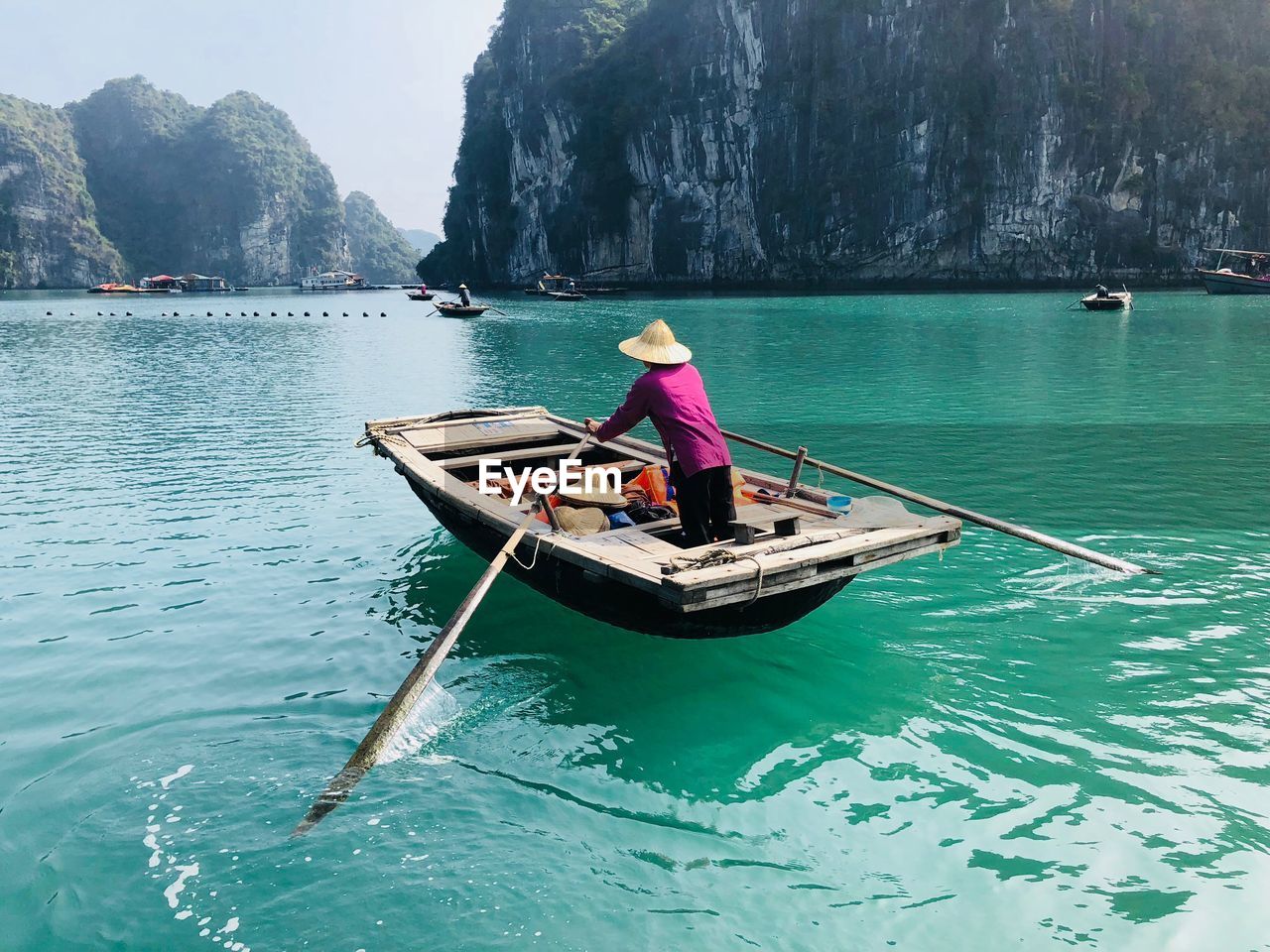 Man in boat sailing on sea against mountains