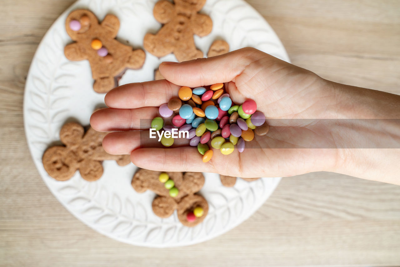 Cropped image of mother hand holding candies over cookies