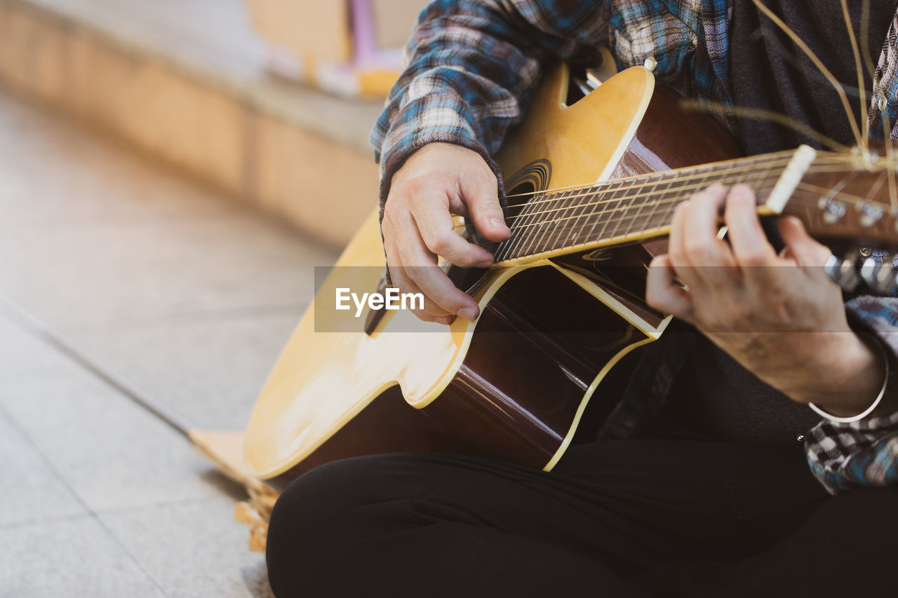 Midsection of man playing guitar