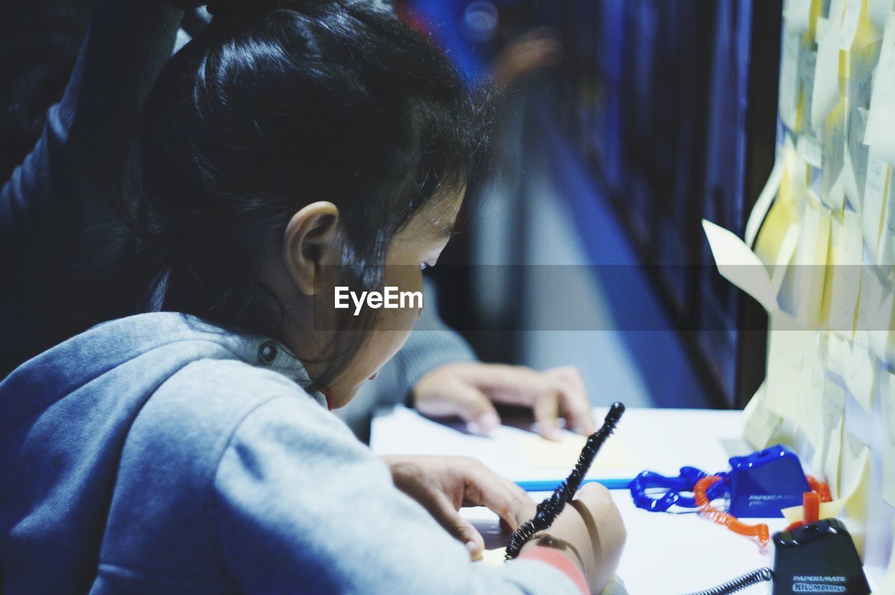 Close-up of girl writing on table