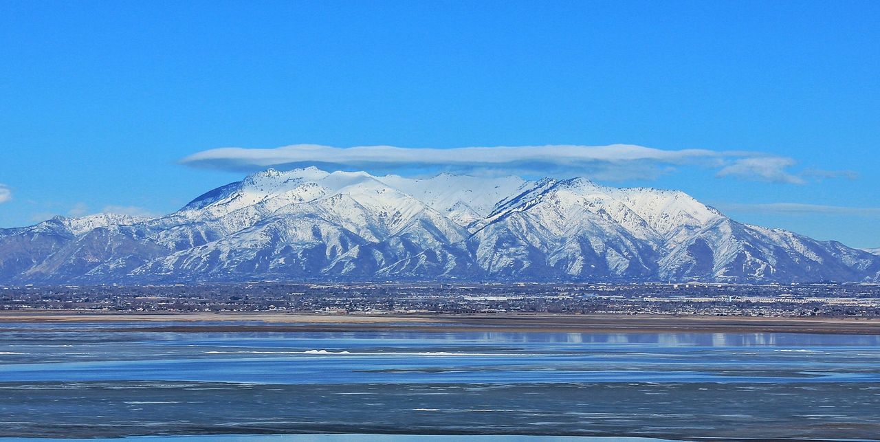 Scenic view of lake and snow covered mountains against sky