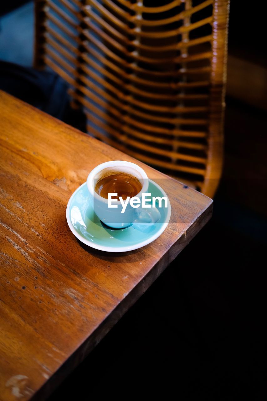 COFFEE CUP ON TABLE AGAINST WOODEN WALL