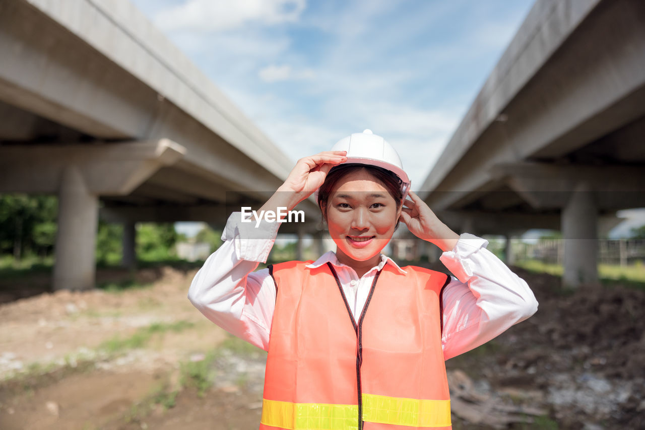 At a building site, a confident female construction worker poses for a portrait.