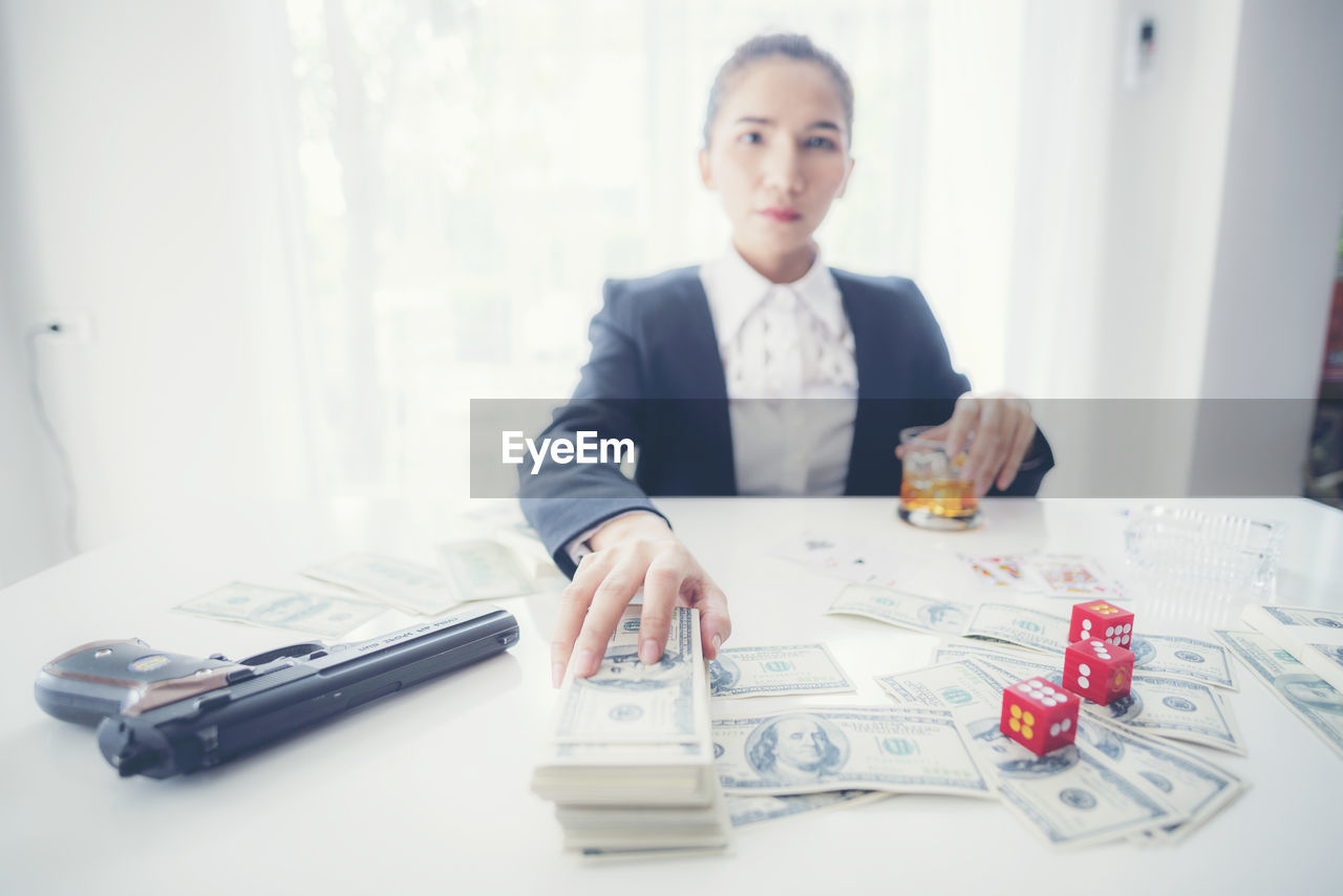 Businesswoman with paper currencies sitting at desk in office