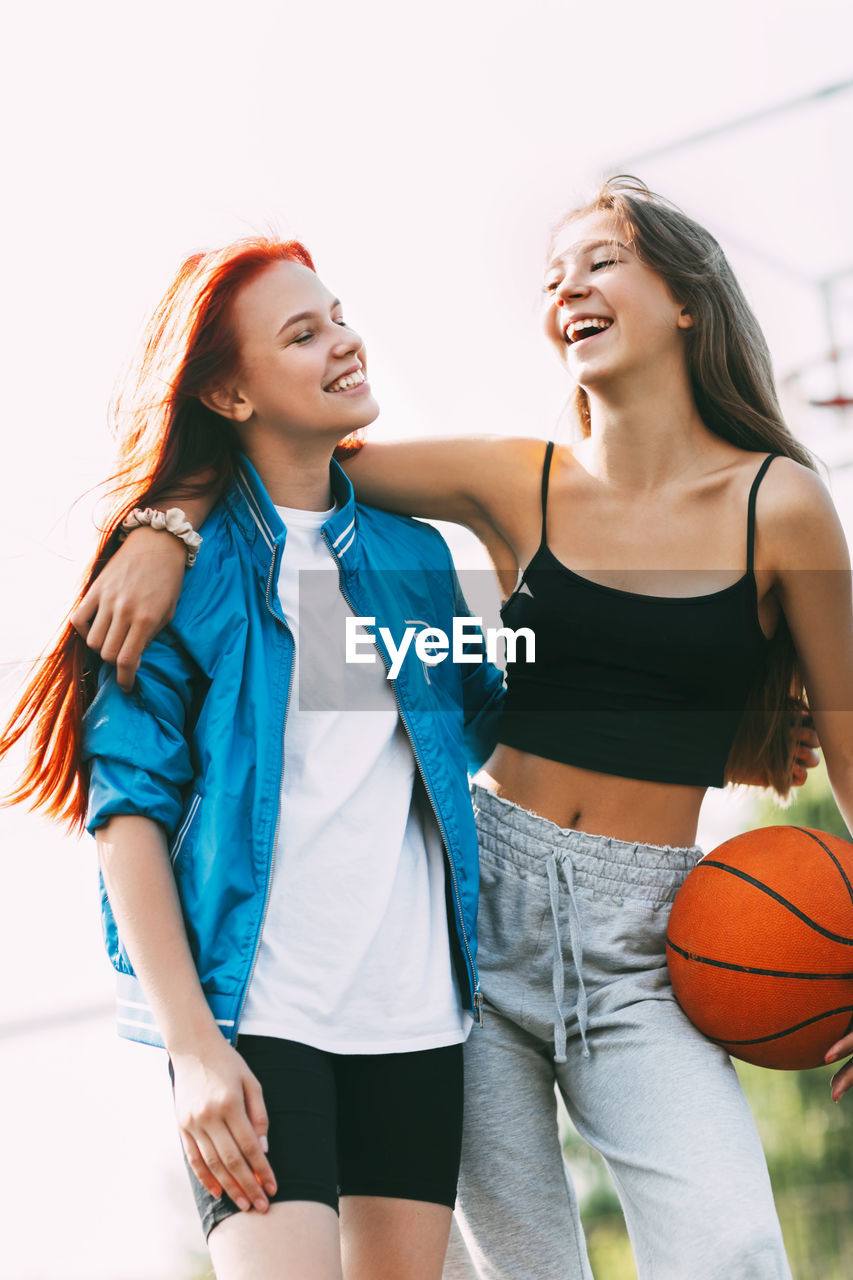 Two funny girls with a basketball hug each other after a game or workout. the concept of sports 