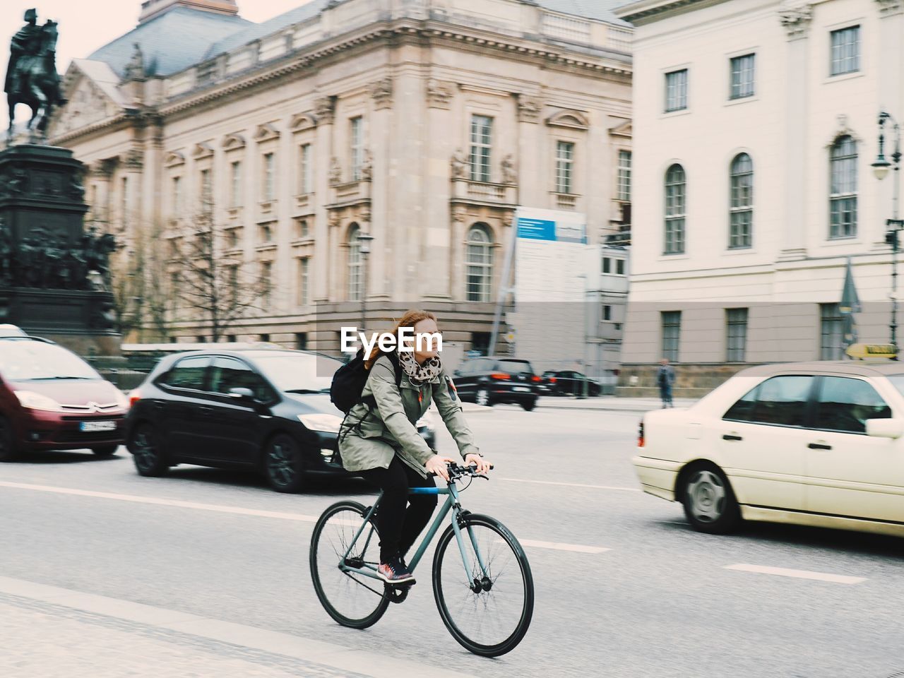Woman riding bicycle on road against buildings in city