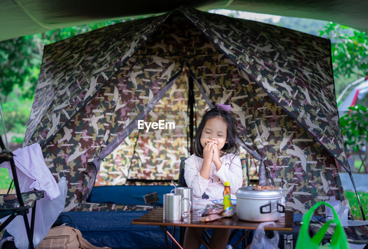 Girl eating while sitting in tent