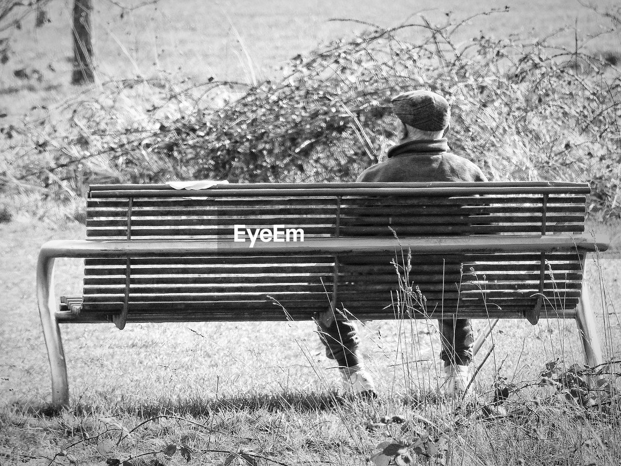 MAN SITTING ON BENCH AGAINST WALL