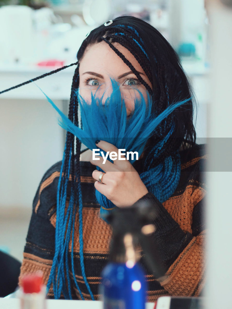 Portrait of woman holding dyed dreadlocks in salon