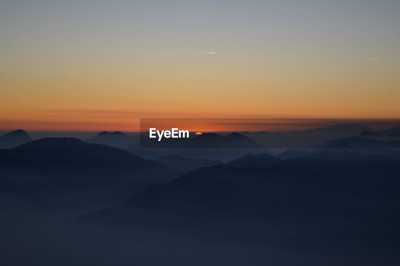 Scenic view of silhouette mountains against sky at sunset