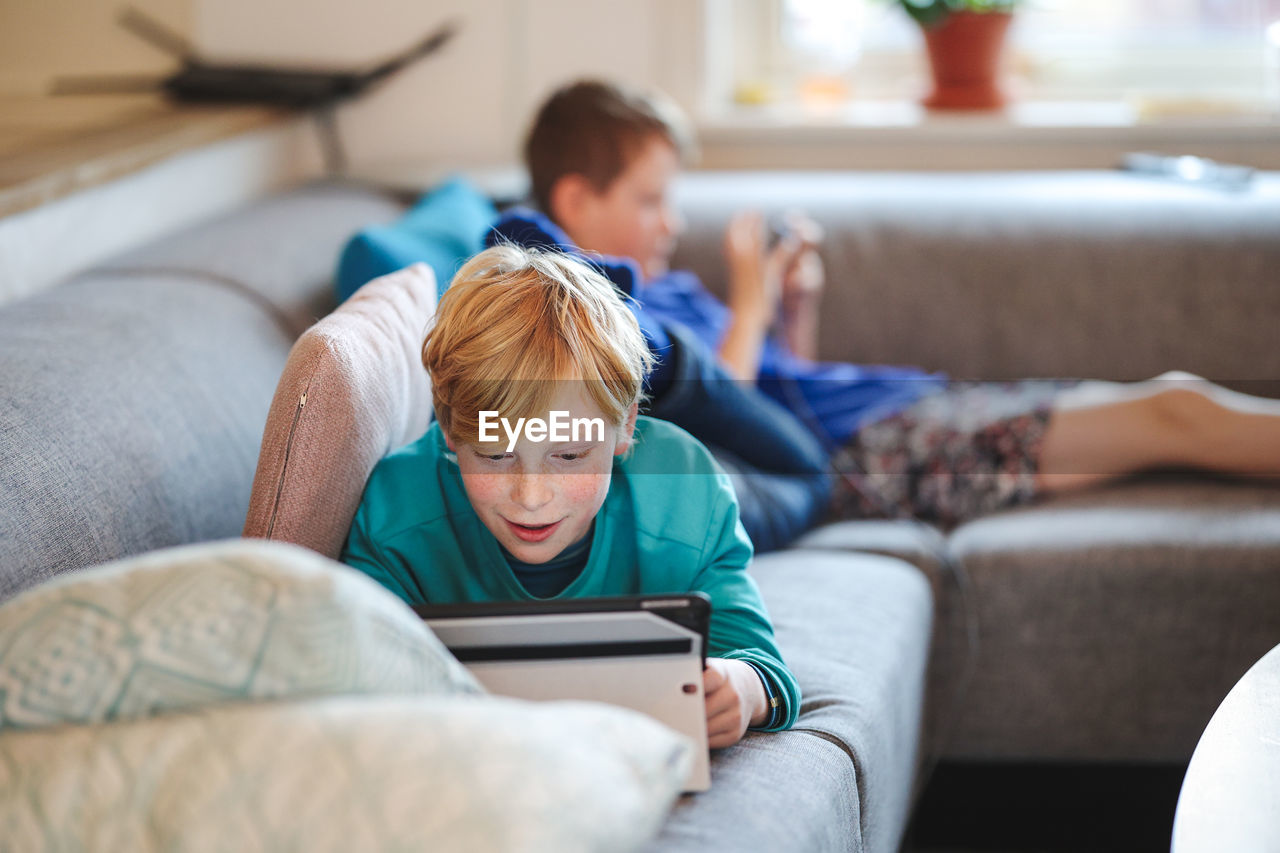 Boys on couch with tablet and phone 