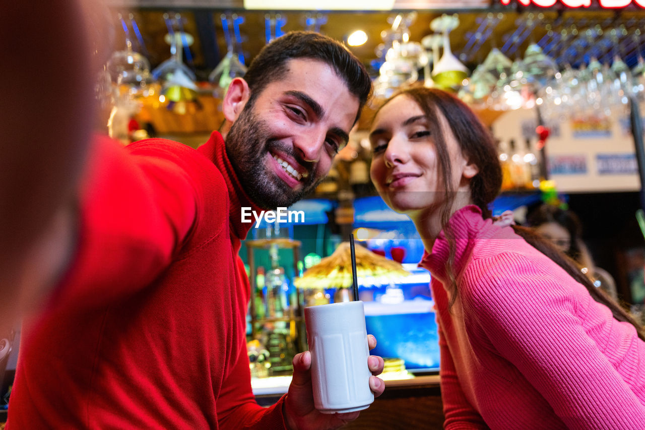 Caucasian happy couple taking selfie and having fun with pub, drinking cocktail - joy concept