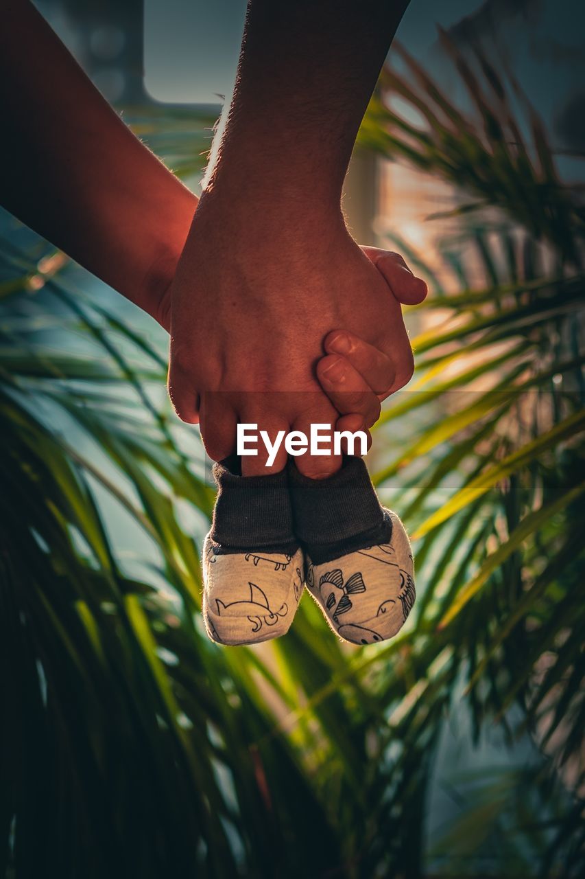 Cropped hands of couple holding baby booties