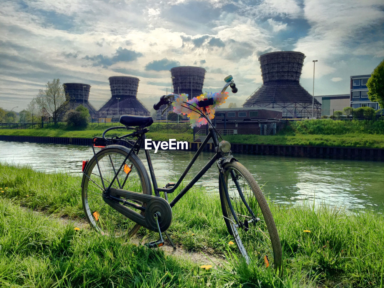 Bicycle parked by river against factory