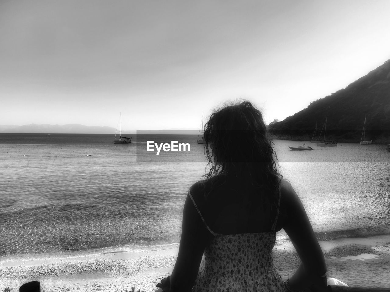 water, black, black and white, one person, sky, land, beach, rear view, monochrome photography, monochrome, white, sea, nature, women, adult, beauty in nature, leisure activity, vacation, tranquility, scenics - nature, trip, holiday, hairstyle, long hair, tranquil scene, lifestyles, solitude, waist up, young adult, day, horizon, cloud, outdoors, standing, three quarter length, relaxation, sunlight, non-urban scene, sitting, person, loneliness, sand, horizon over water, idyllic, dress, female, ocean, contemplation, clothing, looking at view