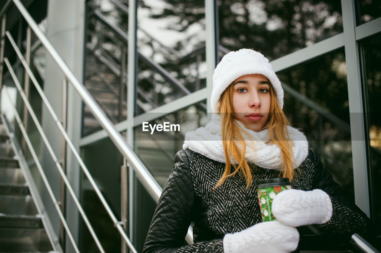 Portrait of young woman wearing warm clothing in city during winter