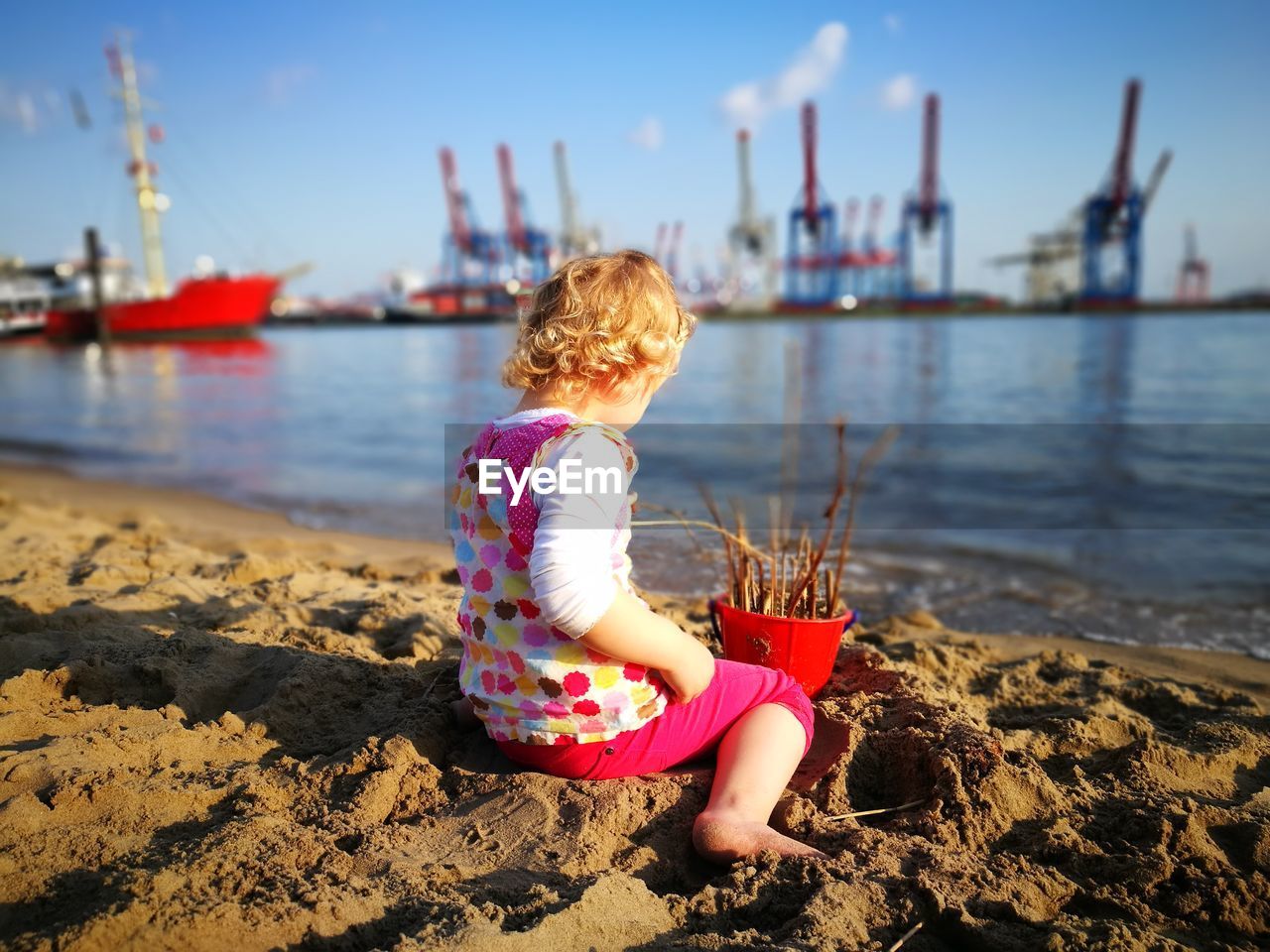 GIRL SITTING ON SHORE AT BEACH