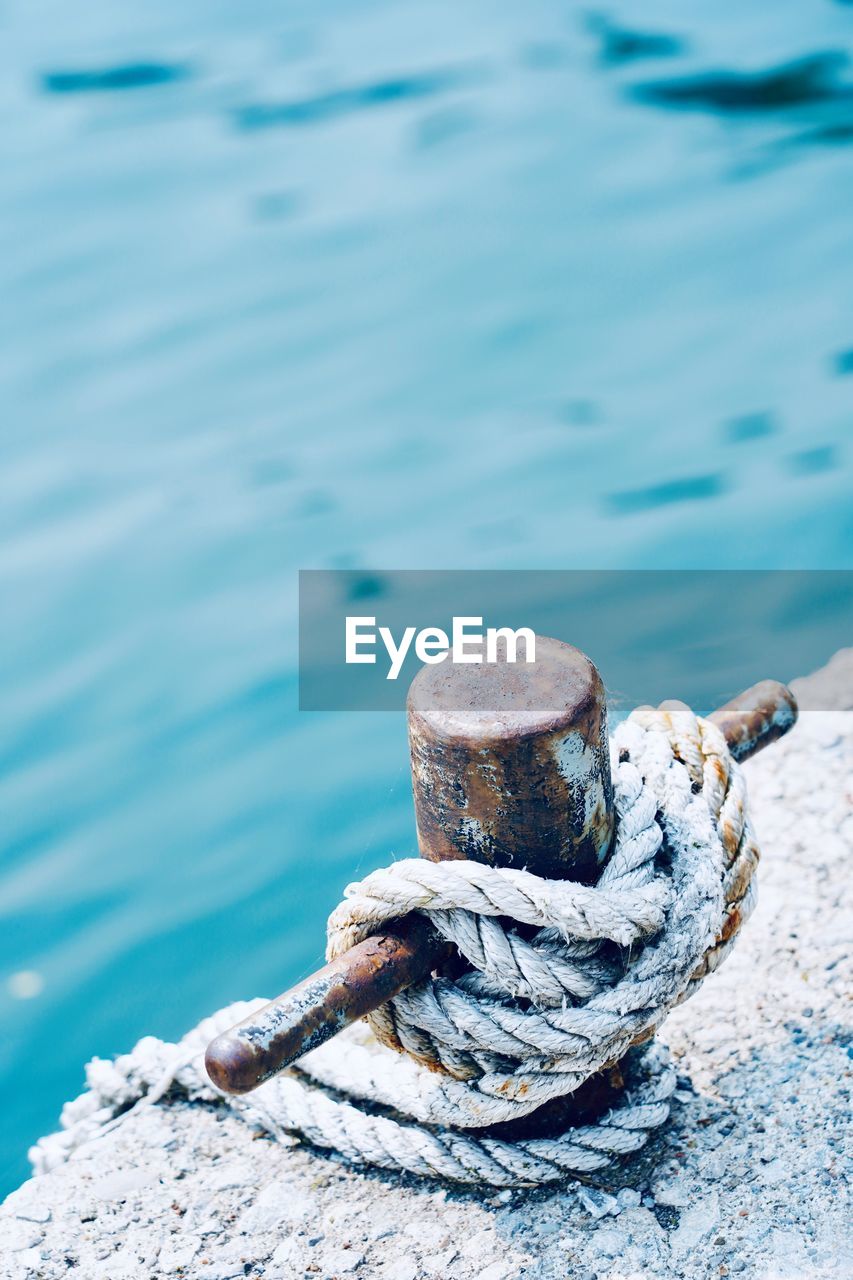 High angle view of rope tied on metal over sea