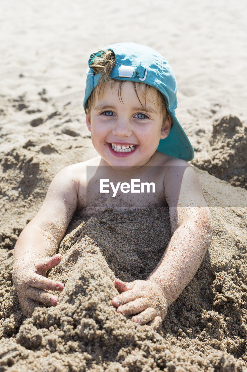 Happy boy buried in sand