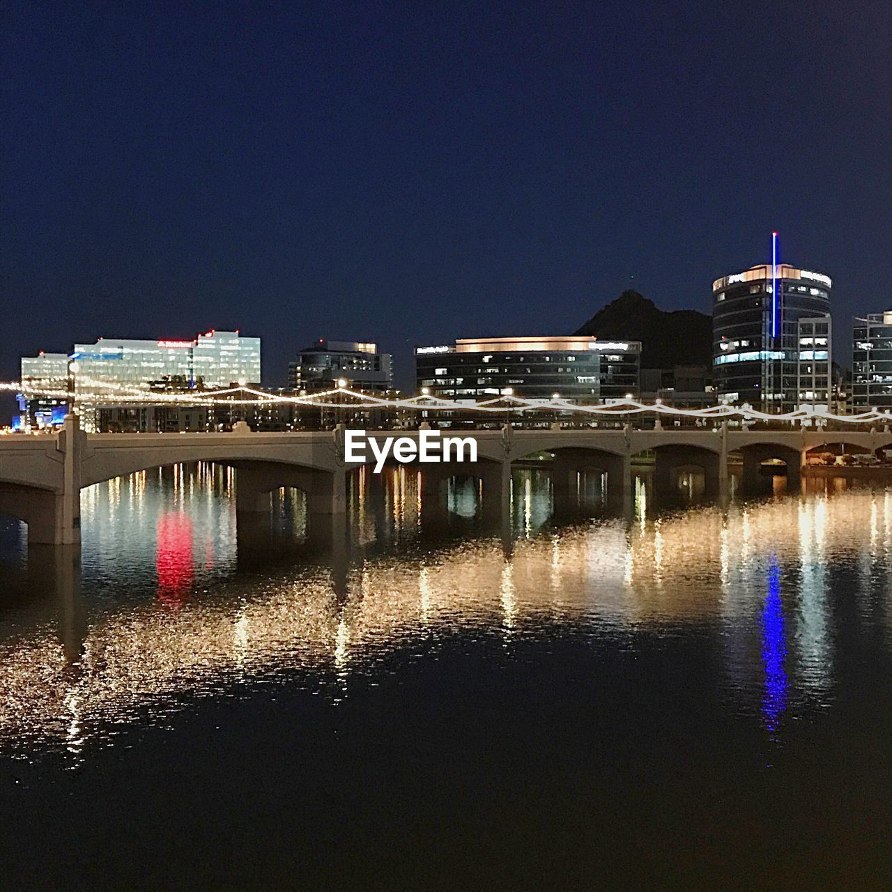 ILLUMINATED BRIDGE OVER RIVER AGAINST SKY AT NIGHT