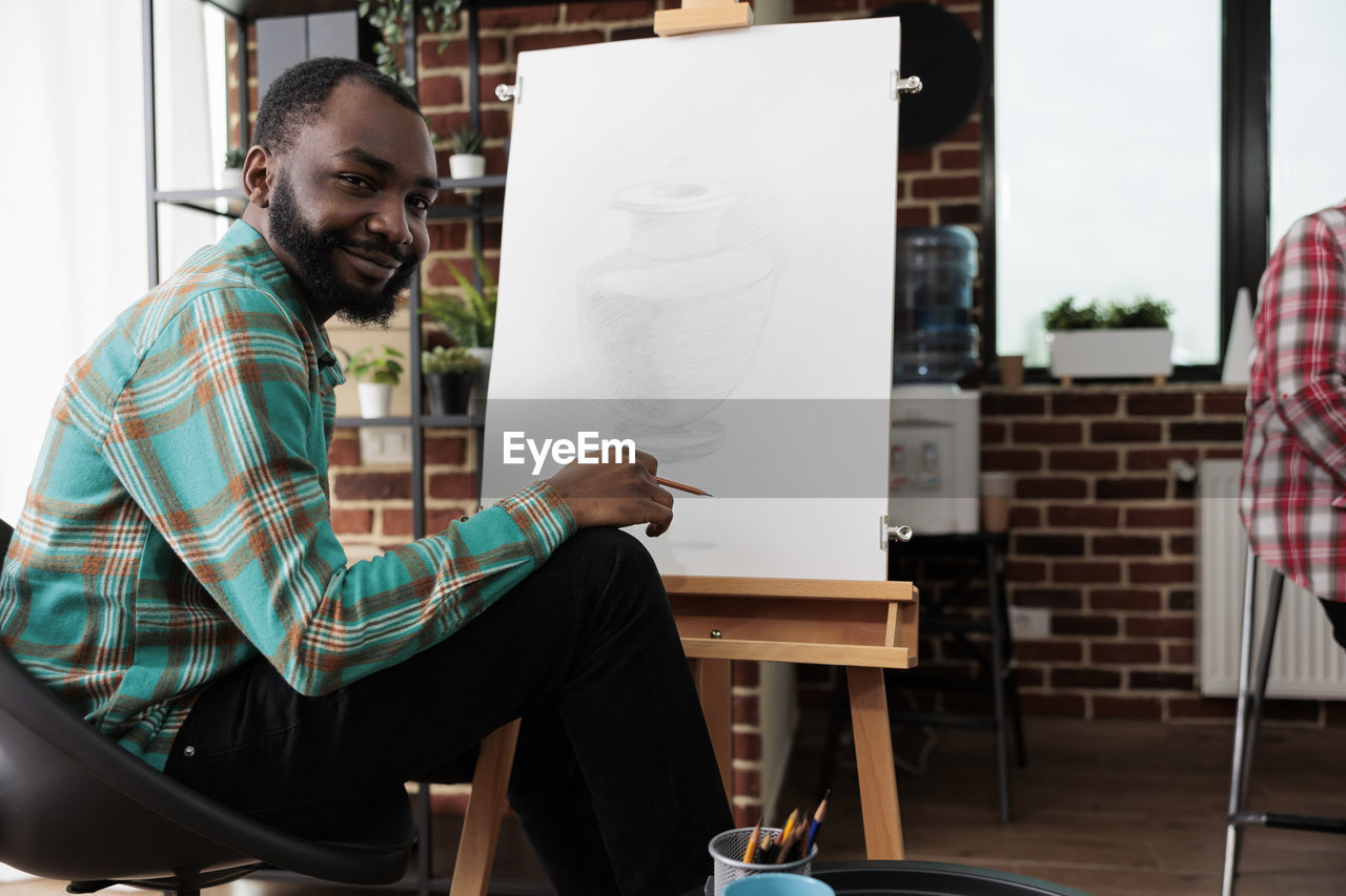 portrait of young man using laptop while sitting on chair