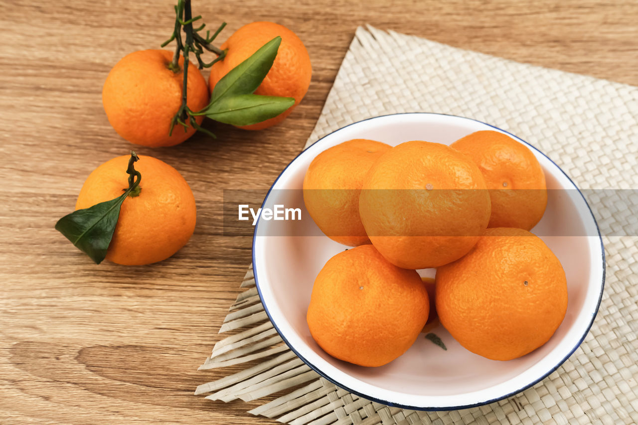 food and drink, food, healthy eating, clementine, fruit, freshness, tangerine, wellbeing, plant, citrus, orange color, produce, citrus fruit, no people, orange, leaf, plant part, still life, wood, bitter orange, indoors, table, group of objects, high angle view, bowl, nature