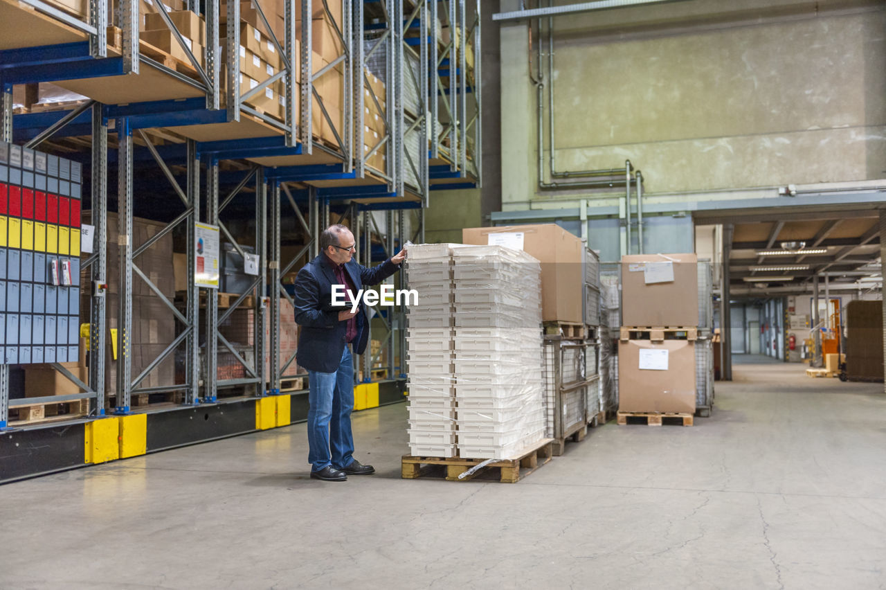 Manager checking goods in storage hall of factory