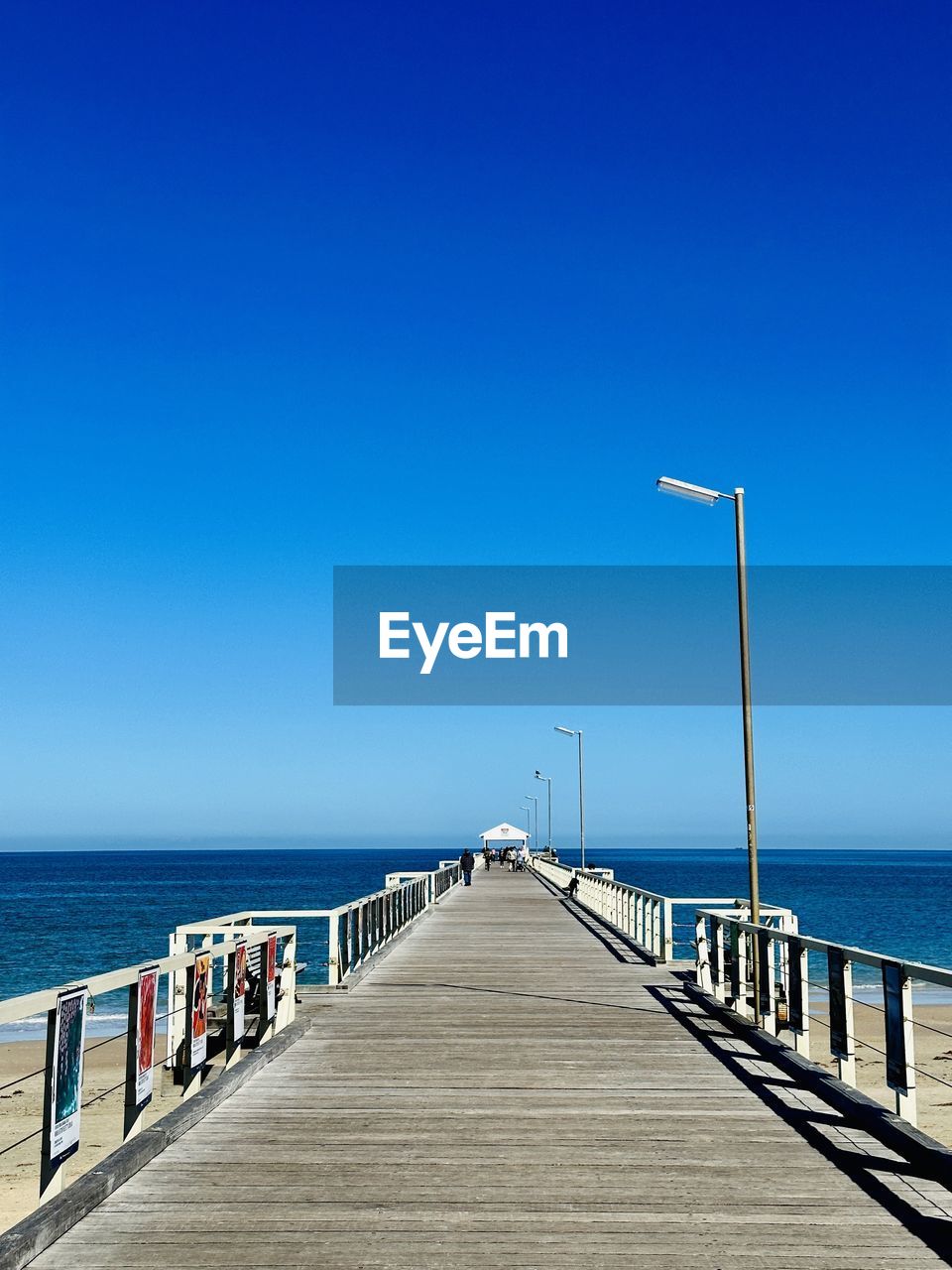water, sky, sea, walkway, ocean, horizon over water, horizon, clear sky, pier, coast, blue, boardwalk, nature, the way forward, beach, scenics - nature, beauty in nature, shore, land, tranquility, vacation, tranquil scene, railing, sunny, wood, copy space, sunlight, day, diminishing perspective, idyllic, architecture, transportation, no people, jetty, outdoors, travel destinations, travel, footpath, holiday, summer, dock, bay, trip, seascape, built structure, vanishing point, non-urban scene, urban skyline, body of water, tourism