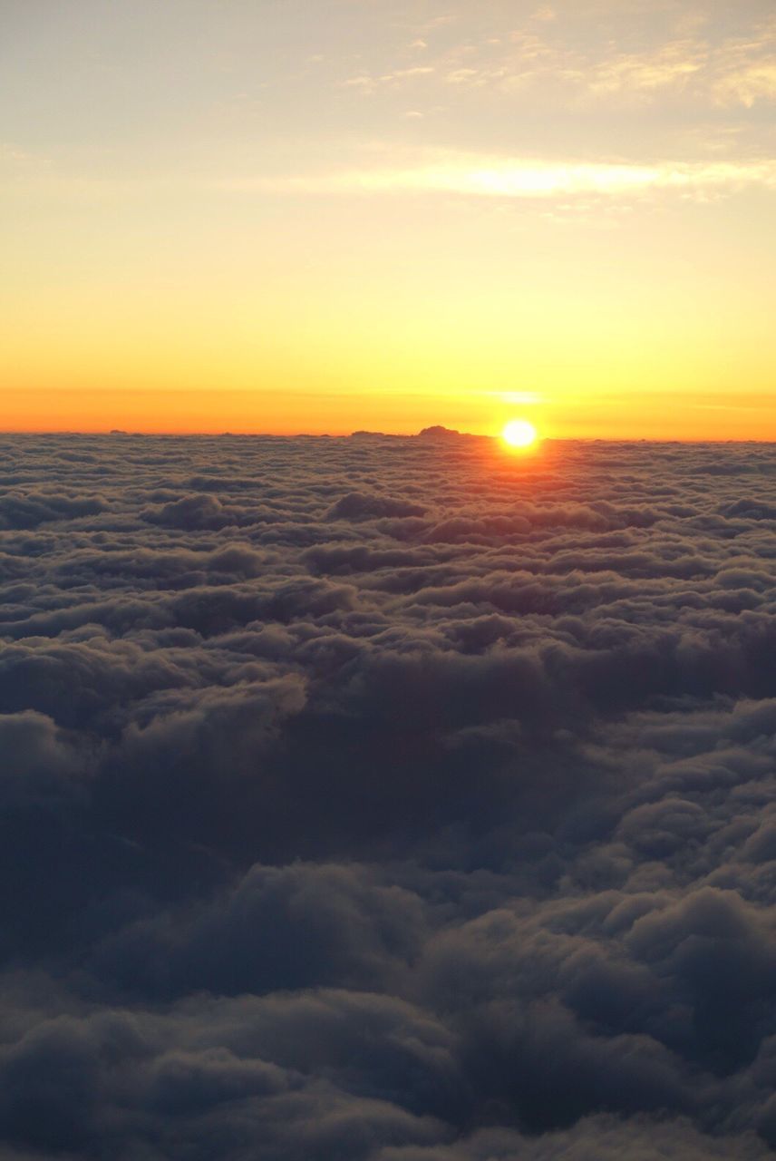 SUN SHINING THROUGH CLOUDS OVER LANDSCAPE