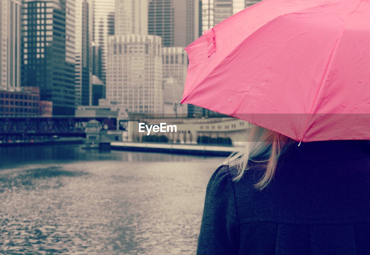 Rear view of woman with umbrella in city