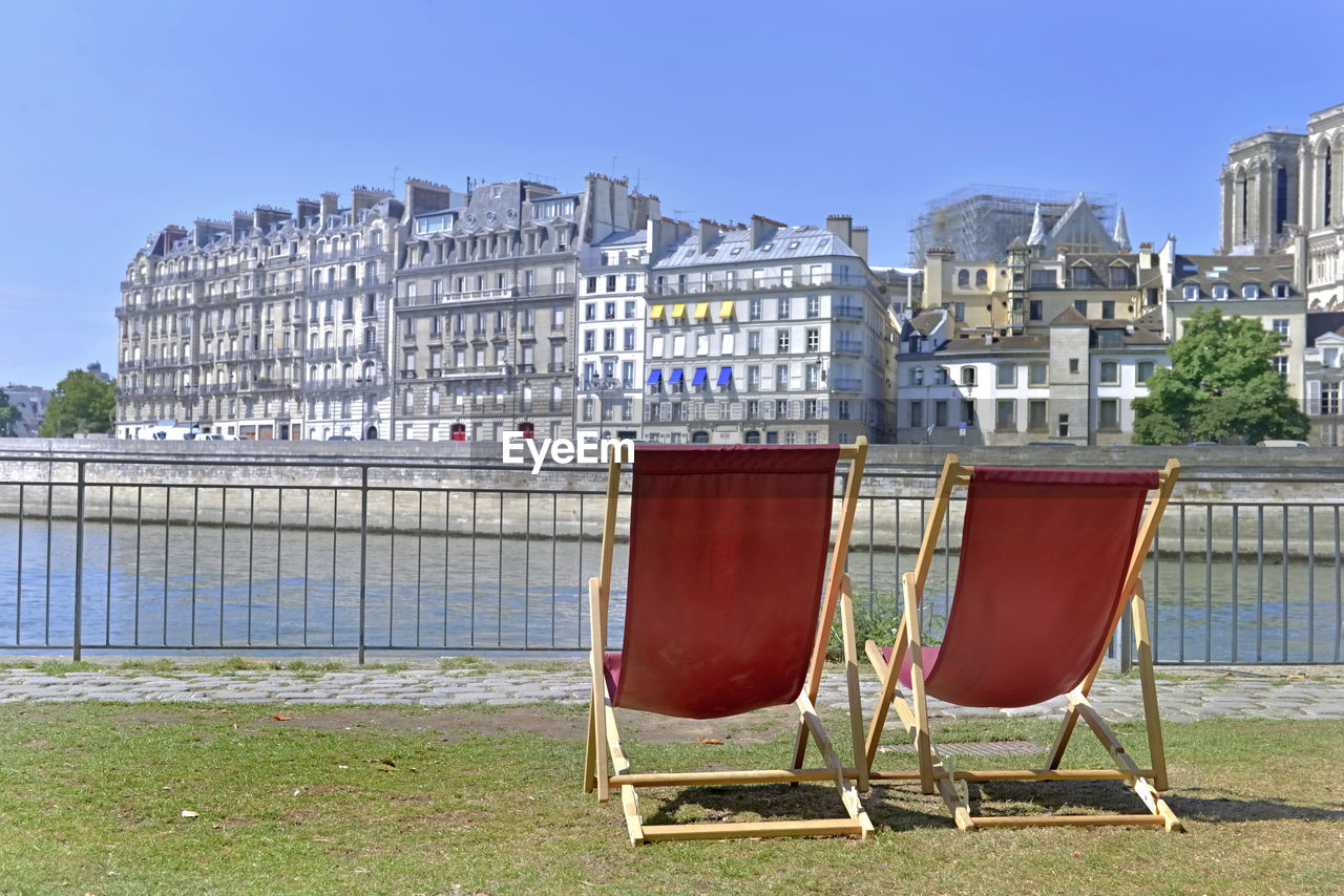 Chairs on field against buildings in city