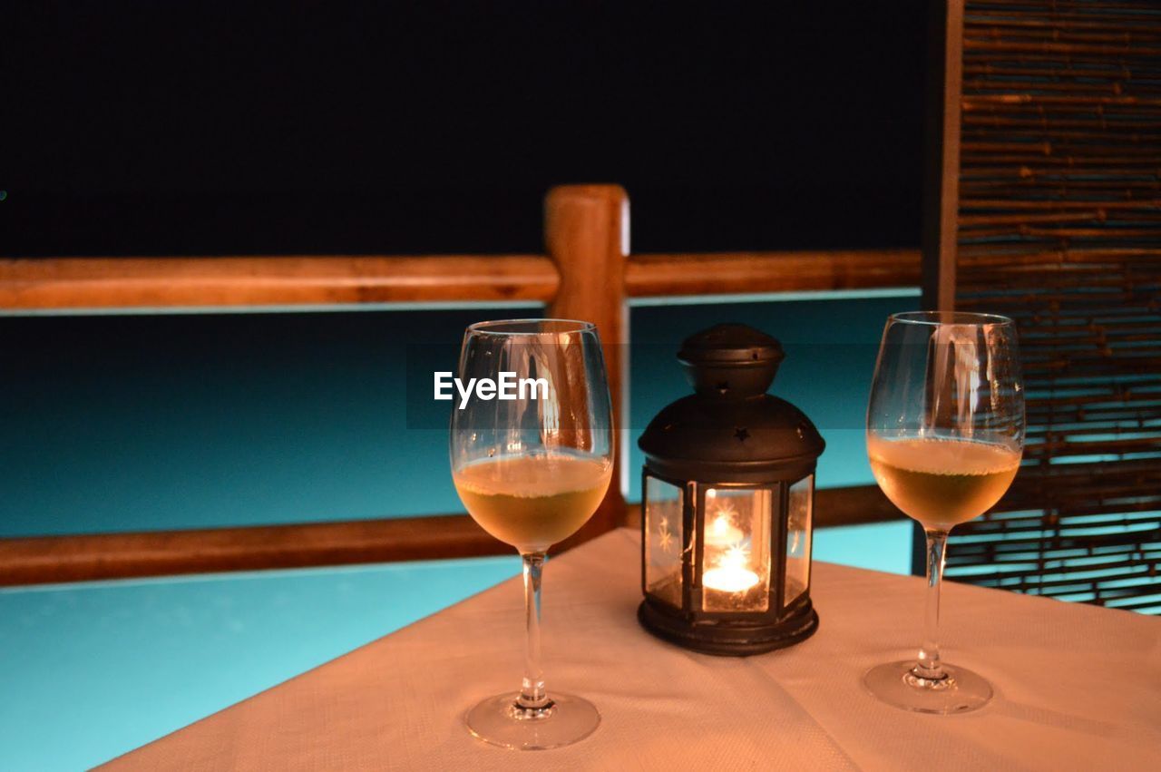 Wineglasses and candle on table at night