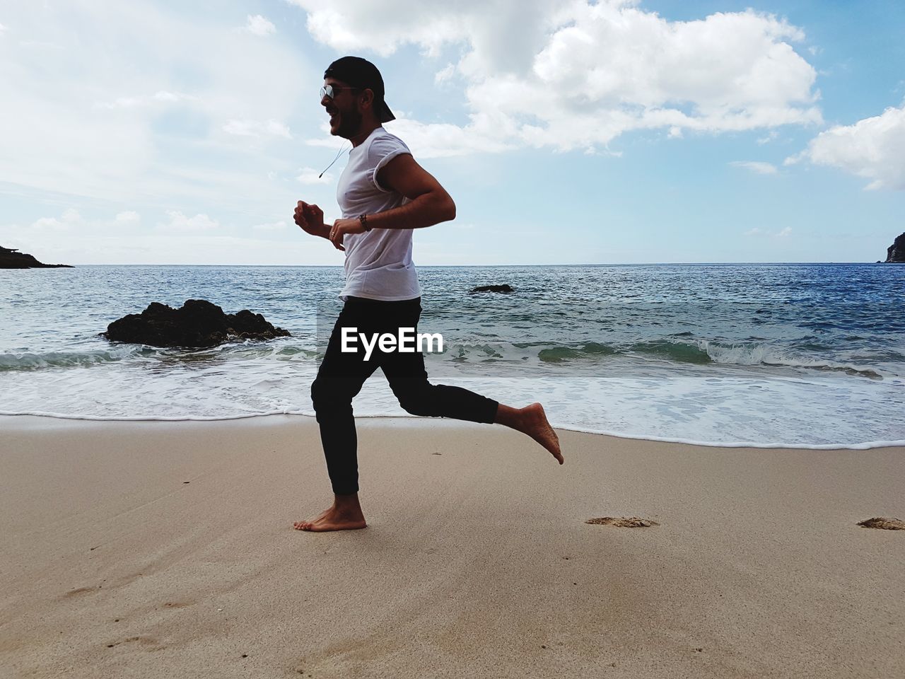 Full length of man running on sand against sea at beach