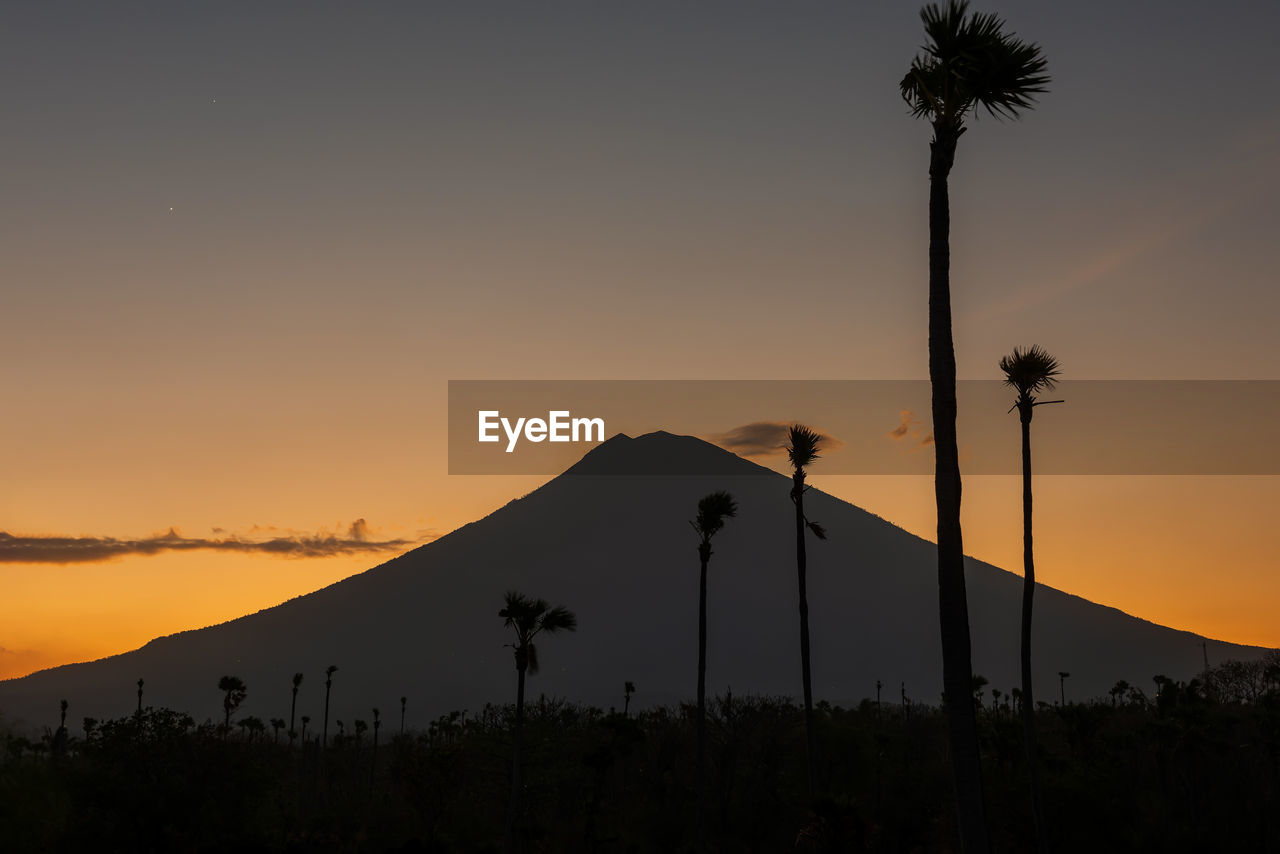 Orange sunset above agung volcano, bali island. volcano view from black sand beach, indonesia.