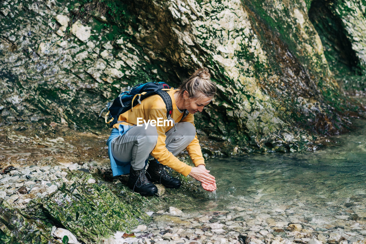 Hiker woman washes her hands in a mountain stream.