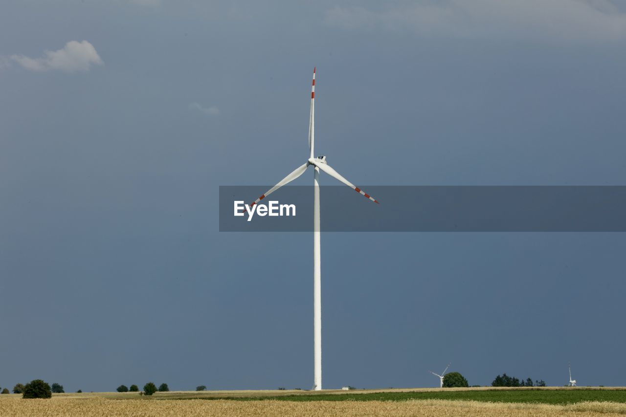 Low angle view of windmill on field against sky