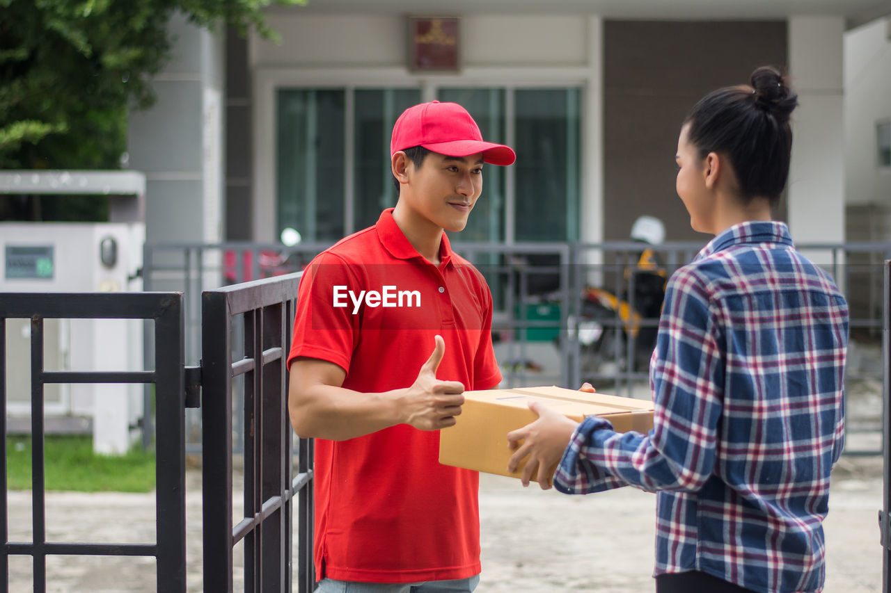 Man delivering package to female customer at gate