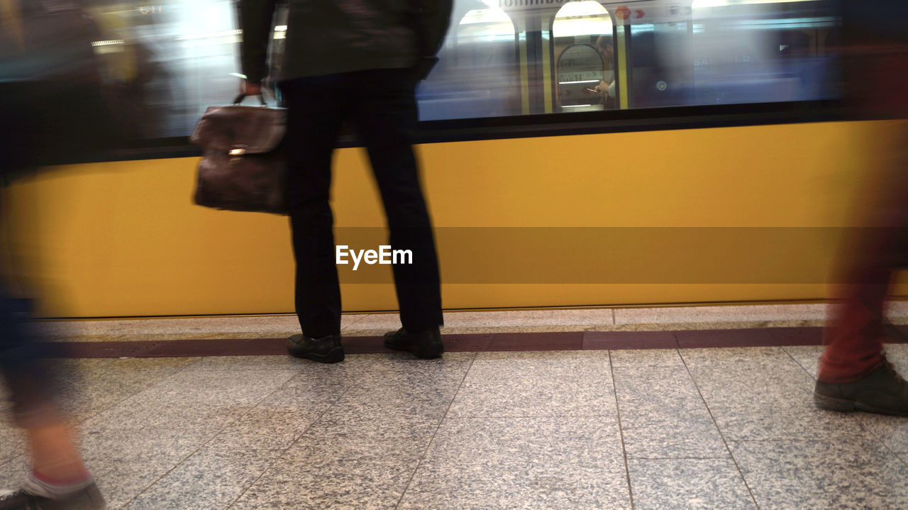 LOW SECTION OF PEOPLE STANDING AT RAILROAD STATION