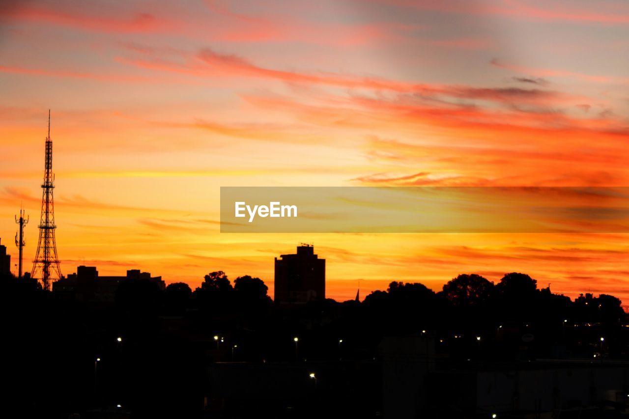 SILHOUETTE OF BUILDINGS AGAINST ORANGE SKY