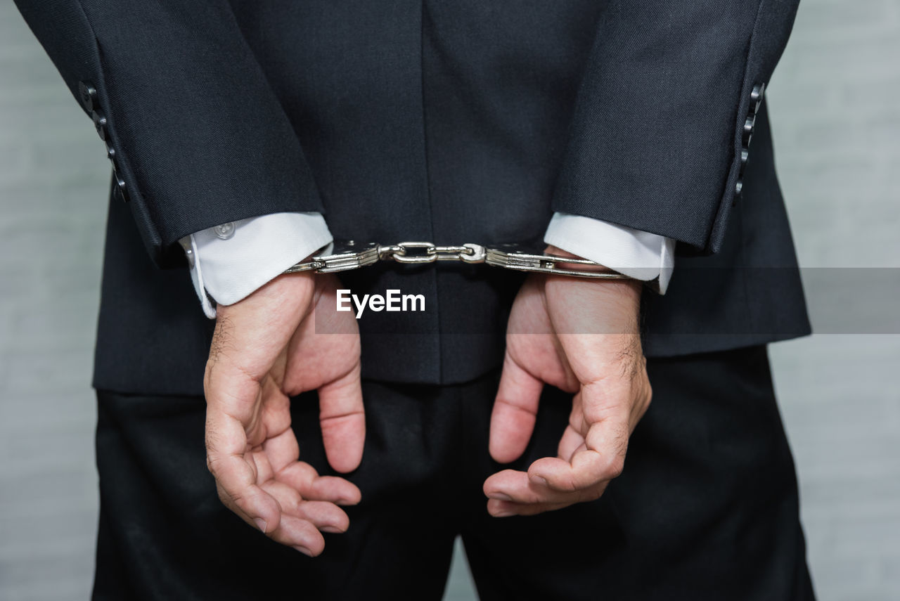 Midsection rear view of businessman with handcuffs