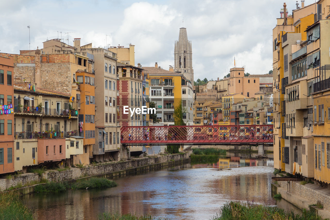 Buildings by river against sky in city