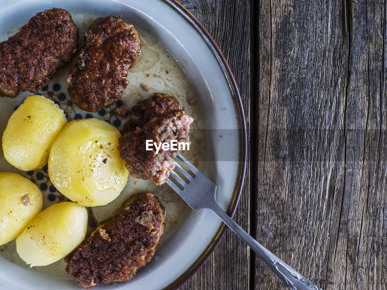 High angle view of deep fried food and potatoes in plate with fork at table