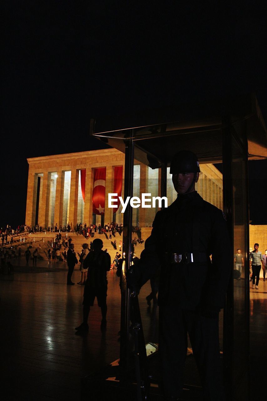 SILHOUETTE PEOPLE STANDING IN ILLUMINATED BUILDING AT NIGHT