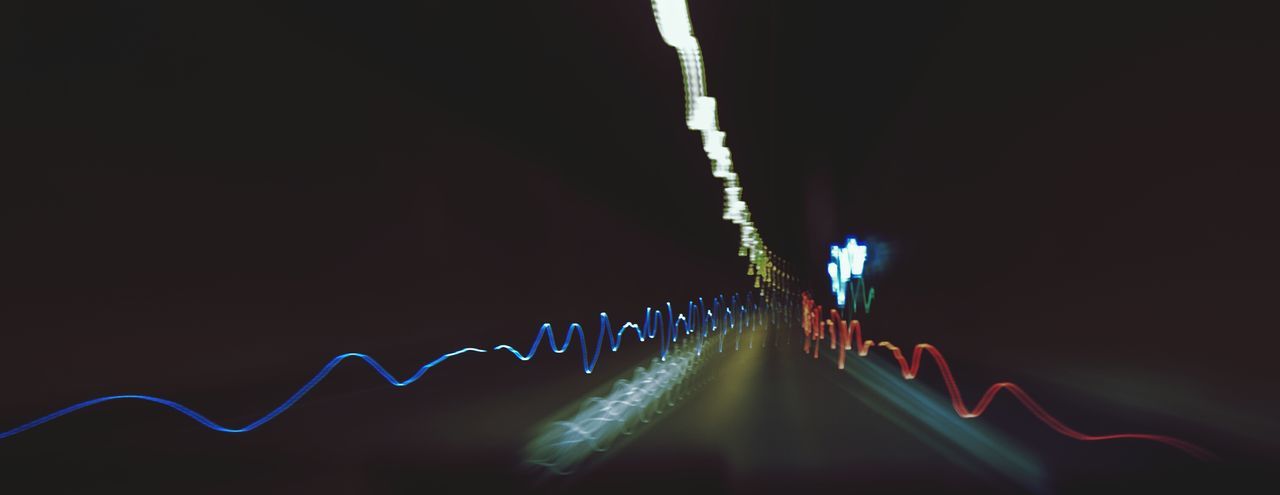 LIGHT TRAILS AGAINST SKY AT NIGHT