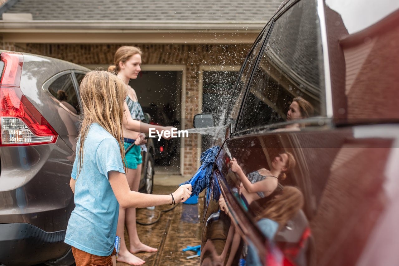 Girls cleaning car in yard