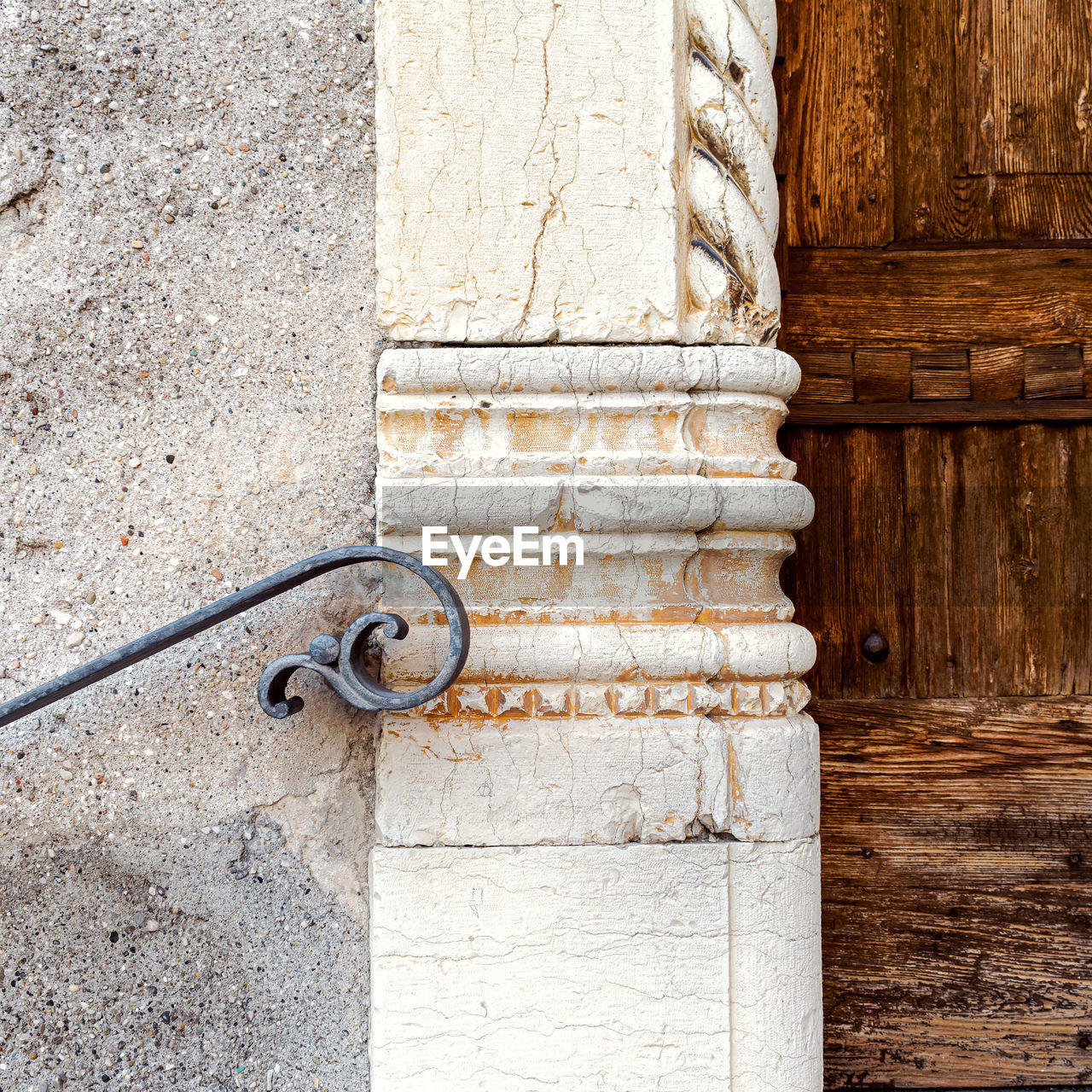 Close-up of closed door on wall, ancient railing and marble decoration